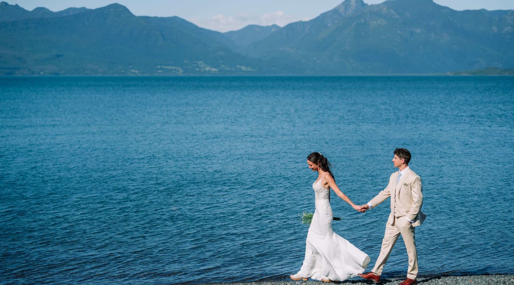 Novios caminando a orillas de un lago tras su ceremonia simbólica